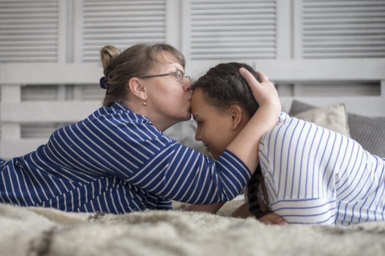 Teen mental health recovery: mom kissing teen celebrating a small win of getting though the day without self-harm.